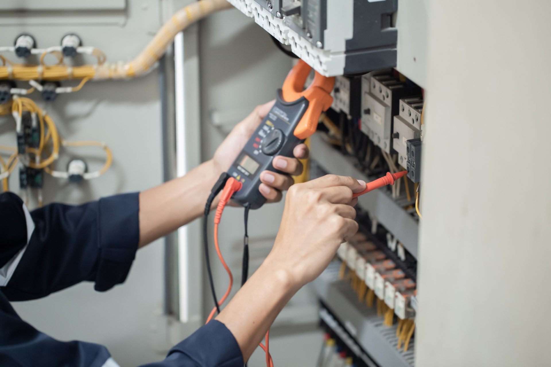 Electrician engineer work tester measuring voltage and current of power electric line in electrical cabinet control , concept check the operation of the electrical system .